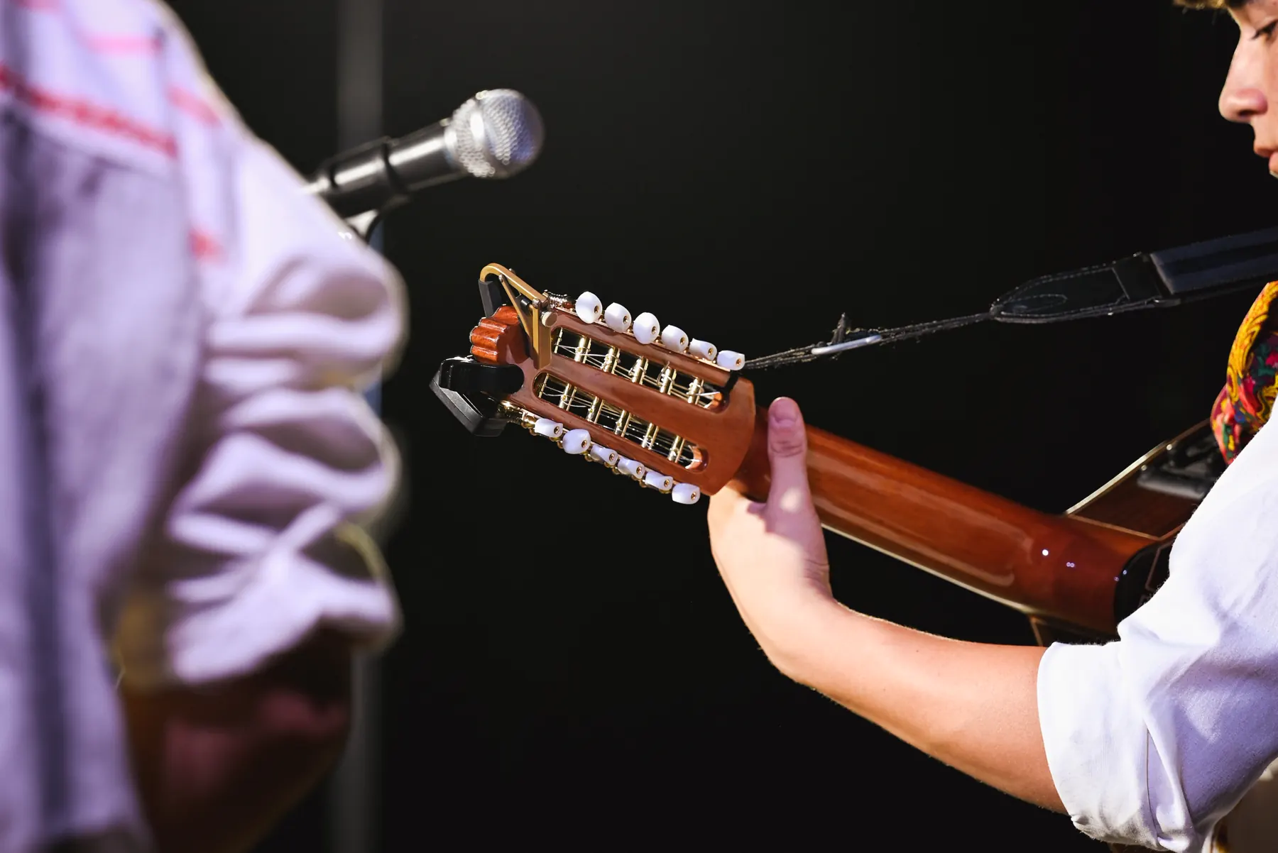 Detalle de las manos de un músico tocando la guitarra en el escenario