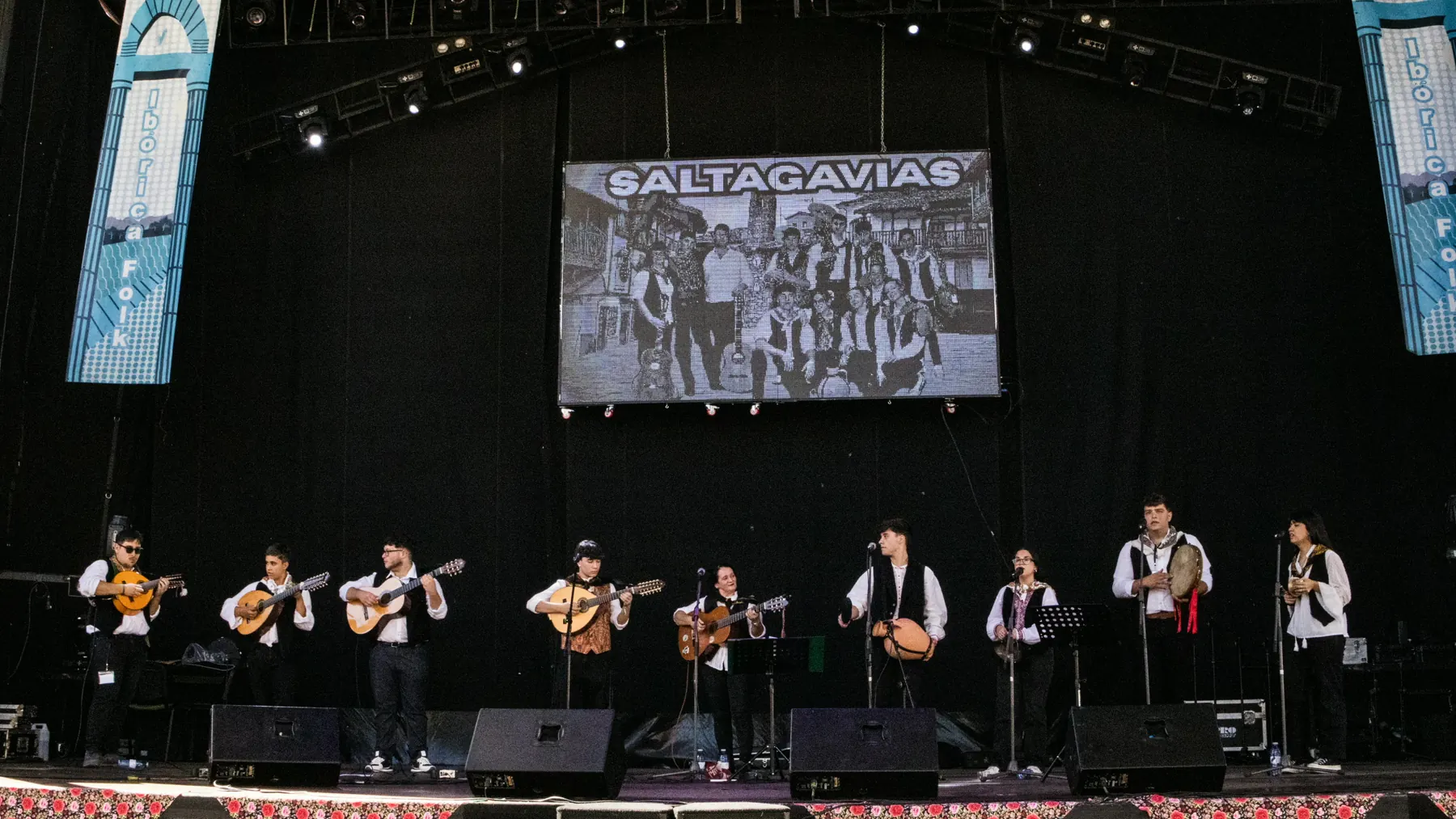 Los Saltagavias tocando en un gran escenario, con su nombre en la pantalla del fondo
